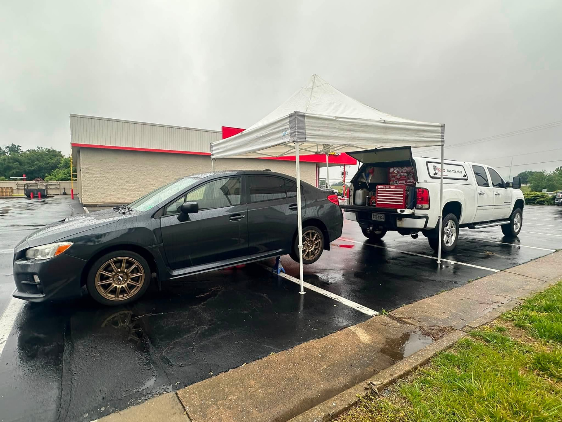 Vehicle getting serviced under a canopy in a parking lot